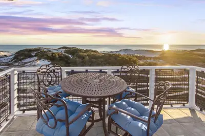a table and chairs on a balcony with a view of the ocean at NEW RENTAL Beach Front Condo in WaterSound Beach FL with Stunning Views! condo in Panama City Beach