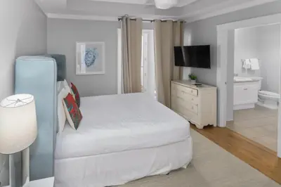 a white bedroom with a bed and a television at Spacious, Gulf Views 110B WaterSound Crossings Steps to Beach and Pool condo in Panama City Beach