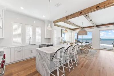 a kitchen with white cabinets and a large island with chairs at Gulf Front Luxurious Home with Private Pool and Beach Access home in Panama City Beach