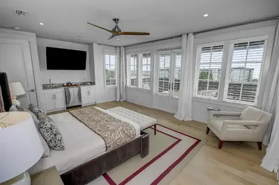 a bedroom with a bed and a chair and windows at Gulf Views, Private Pool, Luxurious Home - Vista Del Mare home in Santa Rosa Beach