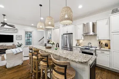a kitchen with white cabinets and a bar with stools at Charming 4 BR Family Beach Retreat - 25 Half Moon, WaterSound West Beach home in Panama City Beach