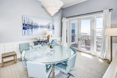 a dining room with a glass table and blue chairs at STUNNING GULF VIEWS - 3BR WaterSound Condo #426A - Steps to Beach and Pool condo in Panama City Beach