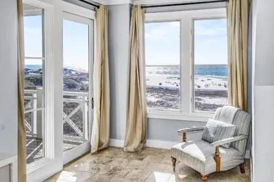 a room with large windows with a chair and the ocean at STUNNING GULF VIEWS - 3BR WaterSound Condo #426A - Steps to Beach and Pool condo in Panama City Beach