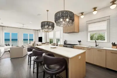 a kitchen with a large island with bar chairs at Shellstone Cottage - Beach Front Seacrest Home with Private Pool and 5 Bedrooms home in Inlet Beach