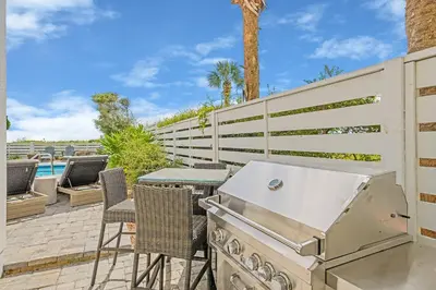 a outdoor kitchen with a grill and a table and chairs at Shellstone Cottage - Beach Front Seacrest Home with Private Pool and 5 Bedrooms home in Inlet Beach