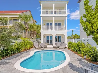a villa with a swimming pool in front of a house at Shellstone Cottage - Beach Front Seacrest Home with Private Pool and 5 Bedrooms home in Inlet Beach
