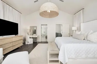 a white bedroom with a large bed and a flat screen tv at Shellstone Cottage - Beach Front Seacrest Home with Private Pool and 5 Bedrooms home in Inlet Beach