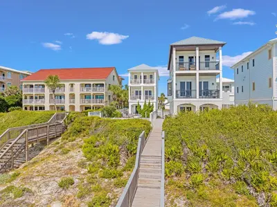 a boardwalk leads up to a row of houses at Shellstone Cottage - Beach Front Seacrest Home with Private Pool and 5 Bedrooms home in Inlet Beach
