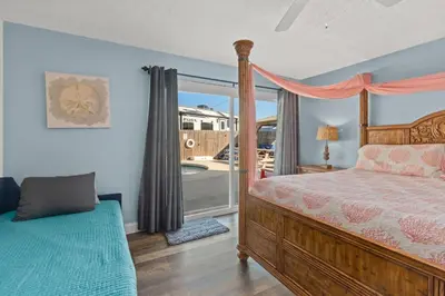a bedroom with a bed and a large window at Anchors Away - Private Pool, Seasonal Hot Tub, Game Room, Walk to Beach, Pets OK in Panama City Beach
