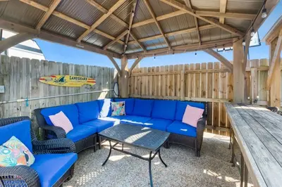 a patio with blue couches and a table at Anchors Away - Private Pool, Seasonal Hot Tub, Game Room, Walk to Beach, Pets OK in Panama City Beach
