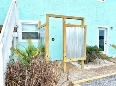 a blue house with a wooden door in front of it at Anchors Away - Private Pool, Seasonal Hot Tub, Game Room, Walk to Beach, Pets OK in Panama City Beach