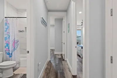 a white bathroom with a toilet and a shower at Sandy Palms - Pool & Hot Tub, 3 Min Walk to the Beach, w Golf Cart & Beach Gear in Panama City Beach