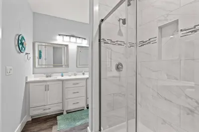 a white bathroom with a shower and a sink at Sandy Palms - Pool & Hot Tub, 3 Min Walk to the Beach, w Golf Cart & Beach Gear in Panama City Beach