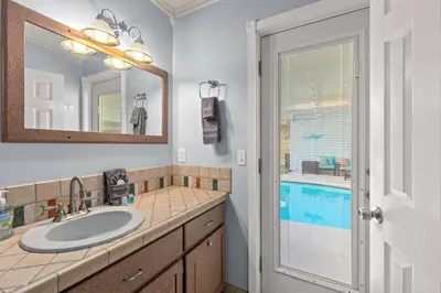 a bathroom with a sink and a mirror and a window at Tiki Hut - Private Pool Home, Game Room, 5 Min Drive 2 Beach, FREE Daily Activities in Panama City Beach