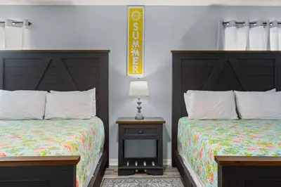 two beds sitting next to each other in a bedroom at Tiki Hut - Private Pool Home, Game Room, 5 Min Drive 2 Beach, FREE Daily Activities in Panama City Beach