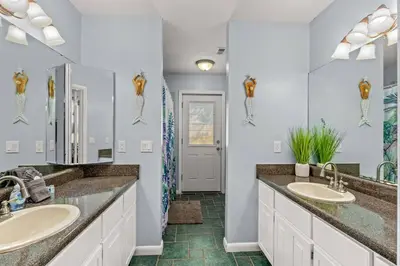 a bathroom with two sinks and a mirror at Tiki Hut - Private Pool Home, Game Room, 5 Min Drive 2 Beach, FREE Daily Activities in Panama City Beach