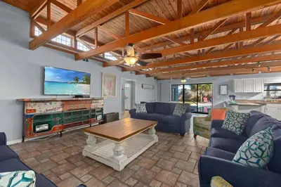 a living room with couches and a table and a tv at Tiki Hut - Private Pool Home, Game Room, 5 Min Drive 2 Beach, FREE Daily Activities in Panama City Beach