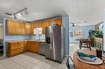 a kitchen with a stainless steel refrigerator and a table at Pirates Cove - Private Pool, Seasonal Hot Tub, Game Room, Close to Beach, Pets OK in Panama City Beach