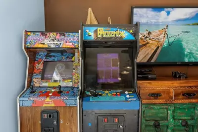 two arcade games sitting next to each other next to a television at Pirates Cove - Private Pool, Seasonal Hot Tub, Game Room, Close to Beach, Pets OK in Panama City Beach