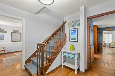 a staircase in a home with white walls and wooden floors at Sand Castle-Pool, Game Rooms, covered outdoor space with tiki bar, 1min walk to beach in Panama City Beach