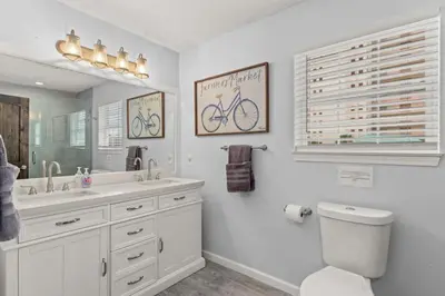 a bathroom with a sink and a toilet and a mirror at Sand Castle-Pool, Game Rooms, covered outdoor space with tiki bar, 1min walk to beach in Panama City Beach
