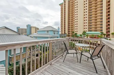 a balcony with two chairs and a table on it at Sand Castle-Pool, Game Rooms, covered outdoor space with tiki bar, 1min walk to beach in Panama City Beach