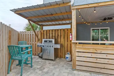 a patio with a stove and a wooden pergola at Sand Castle-Pool, Game Rooms, covered outdoor space with tiki bar, 1min walk to beach in Panama City Beach