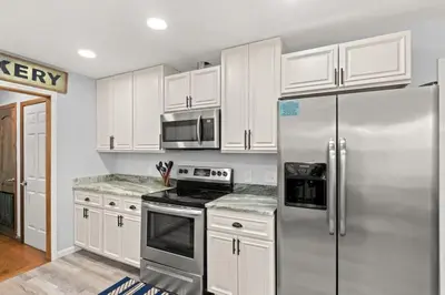 a kitchen with white cabinets and a stainless steel refrigerator at Sand Castle-Pool, Game Rooms, covered outdoor space with tiki bar, 1min walk to beach in Panama City Beach