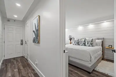 a white bedroom with a bed and a hallway at Summit 803 - Luxury Beach Resort Condo 1-6 People in Panama City Beach