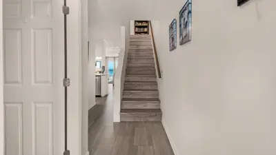 a staircase in a home with white walls and wooden floors at Blue Nine 3 in Panama City Beach