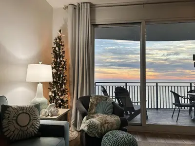 a living room with a christmas tree and a balcony at Sterling Breeze 804 in Panama City Beach