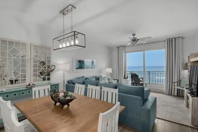 a living room with a blue couch and a table at Sterling Breeze 804 in Panama City Beach