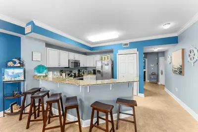 a kitchen with blue walls and wooden stools at Totally Beachin Unit 1302 in Panama City Beach