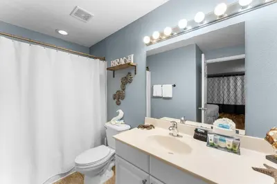 a bathroom with a sink and a toilet and a mirror at Totally Beachin Unit 1302 in Panama City Beach