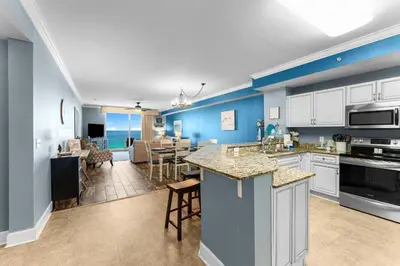 an open kitchen and living room with a view of the ocean at Totally Beachin Unit 1302 in Panama City Beach