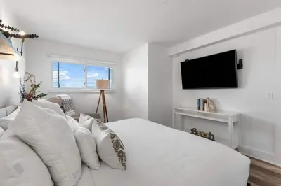 a white bedroom with a white bed and a flat screen tv at Summit 808 - Luxury Beach Resort Condo 1-6 People in Panama City Beach