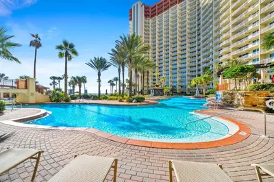 a swimming pool with palm trees and a building at Shores of Panama 431 in Panama City Beach