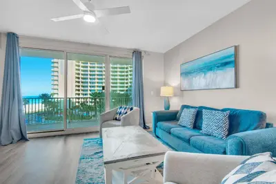 a living room with a blue couch and a balcony at Shores of Panama 426 in Panama City Beach