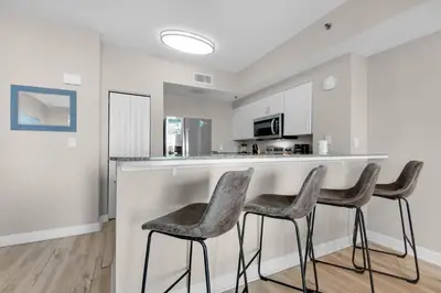 a kitchen with three stools at a bar with a microwave at Shores of Panama 426 in Panama City Beach