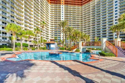 a swimming pool with palm trees and large buildings at Shores of Panama 426 in Panama City Beach