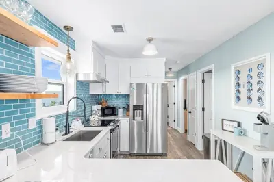 a kitchen with white cabinets and blue tiles at Beachside Villas #731 in Santa Rosa Beach