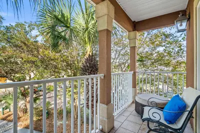 a porch with a chair and a palm tree at LUV PCB by Sand Seeker Vacations in Panama City Beach