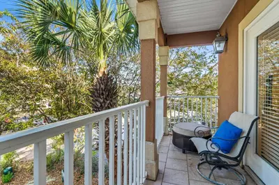 a porch with a chair and a palm tree at LUV PCB by Sand Seeker Vacations in Panama City Beach