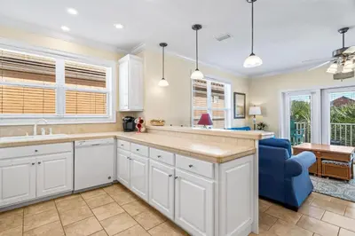 a kitchen with white cabinets and a blue couch at LUV PCB by Sand Seeker Vacations in Panama City Beach