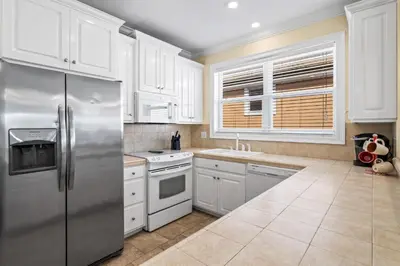 a kitchen with white cabinets and a stainless steel refrigerator at LUV PCB by Sand Seeker Vacations in Panama City Beach
