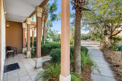 a porch with palm trees and a sidewalk at LUV PCB by Sand Seeker Vacations in Panama City Beach