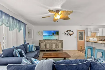 a living room with blue couches and a ceiling fan at Flirty Flamingo with Private Heated Pool, Game Room, and AMAZING Covered Outdoor Living in Panama City Beach