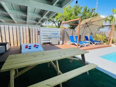 a wooden deck with a picnic table next to a pool at Flirty Flamingo with Private Heated Pool, Game Room, and AMAZING Covered Outdoor Living in Panama City Beach