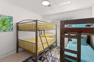 a room with two bunk beds in a room at Flirty Flamingo with Private Heated Pool, Game Room, and AMAZING Covered Outdoor Living in Panama City Beach