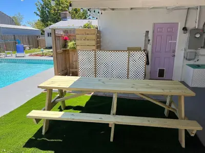 a wooden picnic table sitting next to a pool at Flirty Flamingo with Private Heated Pool, Game Room, and AMAZING Covered Outdoor Living in Panama City Beach